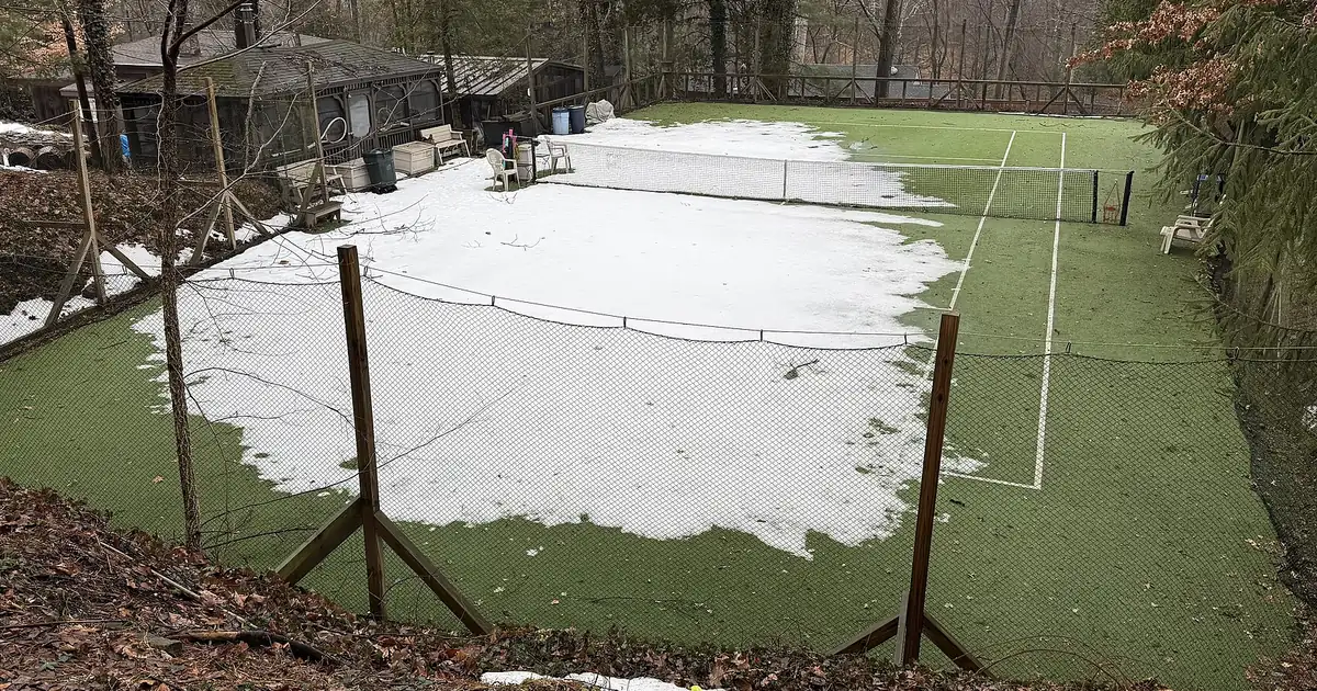 Court de tennis extérieur en hiver, à moitié recouvert de neige, filet tendu