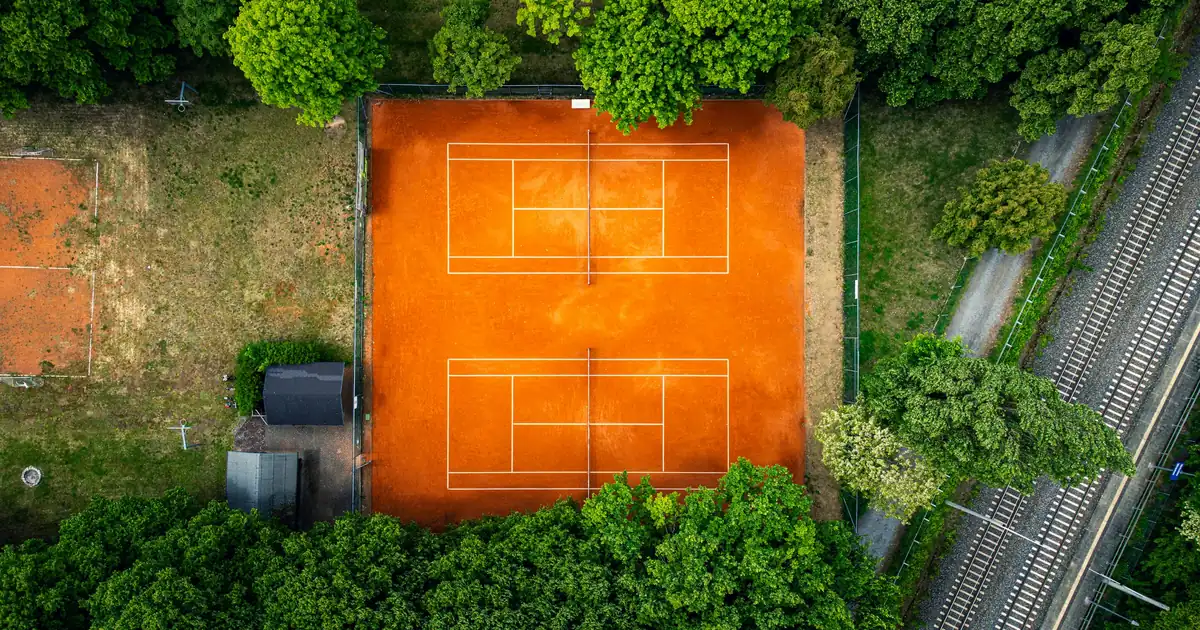 Vue aérienne d'un court de terre battue entouré d'arbres
